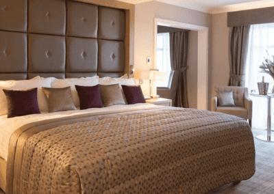 Interior of Carden Park Hotel, a luxury boutique hotel with sophisticated bedrooms, featuring bespoke headboards and furniture with elegant styling.