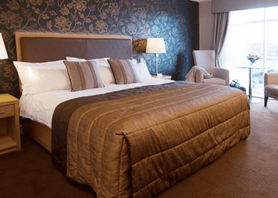 Interior of Carden Park Hotel, a luxury boutique hotel with sophisticated bedrooms, featuring bespoke headboards and furniture with elegant styling.