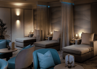 Interior of a hotel pool and spa area, featuring relaxing and comfortable lounge day beds, lounge chairs, and sofas for a calm and serene atmosphere.