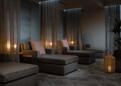 Interior of a hotel pool and spa area, featuring relaxing and comfortable lounge day beds, lounge chairs, and sofas for a calm and serene atmosphere.