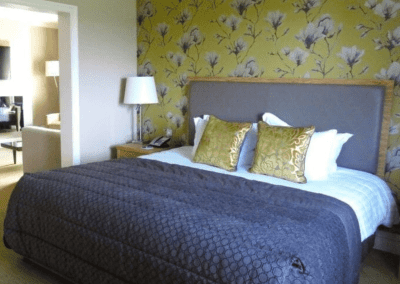 Interior of a luxury boutique hotel with sophisticated bedrooms, featuring bespoke headboards and furniture with elegant styling.