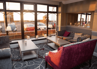 Interiors of a coastal hotel featuring contract furniture, lounge seating, bedroom furniture, and bespoke curtains, pelmets, and blinds reflecting the hotel’s vibrant coastal design.