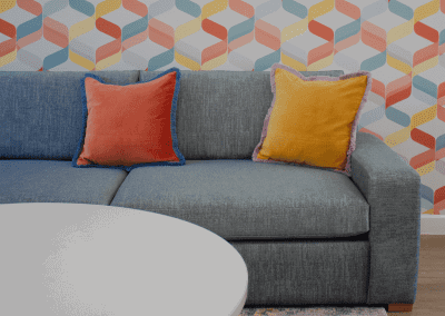 Refurbished common room, featuring durable compact sofas, tub chairs, and dining furniture in uplifting tones.