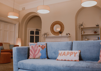 Refurbished common room, featuring durable compact sofas, tub chairs, and dining furniture in uplifting tones.