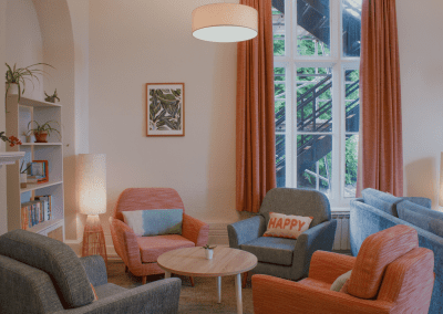 Refurbished common room, featuring durable compact sofas, tub chairs, and dining furniture in uplifting tones.
