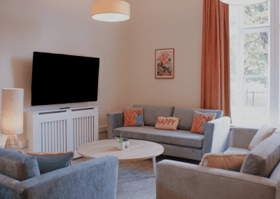 Refurbished common room, featuring durable compact sofas, tub chairs, and dining furniture in uplifting tones.