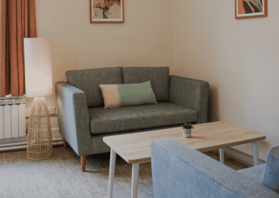 Refurbished common room, featuring durable compact sofas, tub chairs, and dining furniture in uplifting tones.