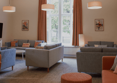 Refurbished common room, featuring durable compact sofas, tub chairs, and dining furniture in uplifting tones.
