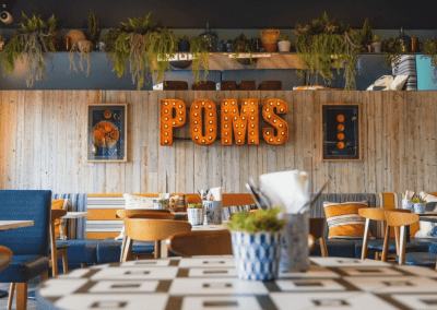 Interior of Poms Barton Marina, Burton-on-Trent, featuring rustic oak-top tables, upholstered café chairs, and fixed seating benches, creating a stylish and inviting waterfront café atmosphere.
