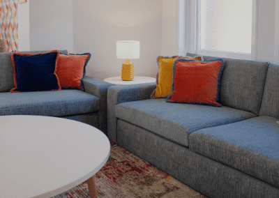 Refurbished common room, featuring durable compact sofas, tub chairs, and dining furniture in uplifting tones.