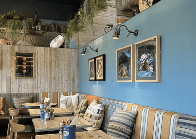 Interior of Poms Barton Marina, Burton-on-Trent, featuring rustic oak-top tables, upholstered café chairs, and fixed seating benches, creating a stylish and inviting waterfront café atmosphere.