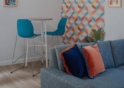 Refurbished common room, featuring durable compact sofas, tub chairs, and dining furniture in uplifting tones.
