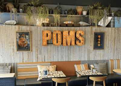Interior of Poms Barton Marina, Burton-on-Trent, featuring rustic oak-top tables, upholstered café chairs, and fixed seating benches, creating a stylish and inviting waterfront café atmosphere.