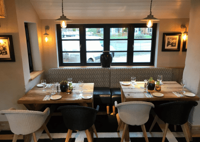 A stylish country pub interior, featuring bespoke dining chairs, tub chairs, and fixed seating made by Jameson Seating.