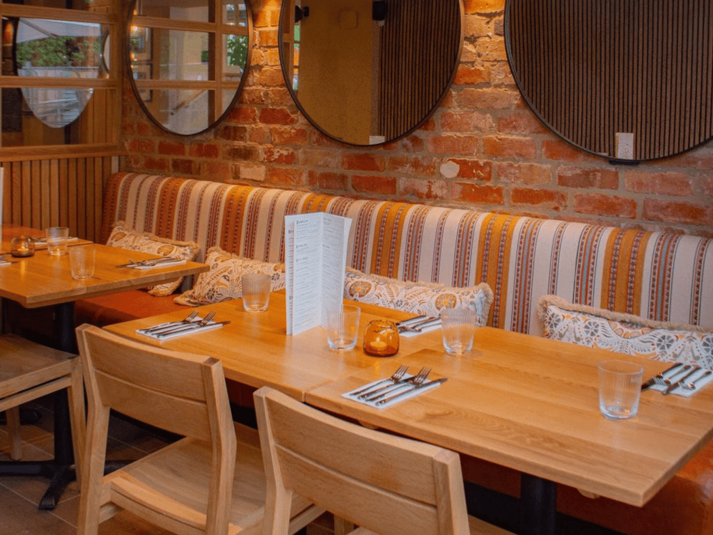 Interior of The Tap & Run pub in Upper Broughton, featuring bespoke bar stools, dining chairs, tables, curtains, and cushions to create a cricket-inspired atmosphere.
