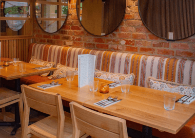 Interior of The Tap & Run pub in Upper Broughton, featuring bespoke bar stools, dining chairs, tables, curtains, and cushions to create a cricket-inspired atmosphere.
