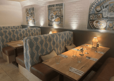 Bespoke pub furniture and soft furnishings featuring comfortable seating, dining tables, and curtains designed to complement the venue’s warm, rustic interior.
