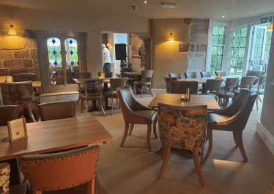 Bespoke pub furniture and soft furnishings featuring comfortable seating, dining tables, and curtains designed to complement the venue’s warm, rustic interior.