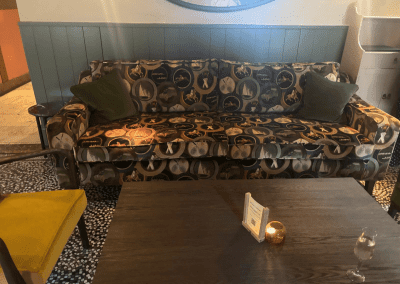 Bespoke pub furniture and soft furnishings featuring comfortable seating, dining tables, and curtains designed to complement the venue’s warm, rustic interior.