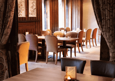 Bespoke pub furniture and soft furnishings at The Long Hop Pub, featuring comfortable seating, dining tables, and curtains designed to complement the venue’s warm, rustic interior.