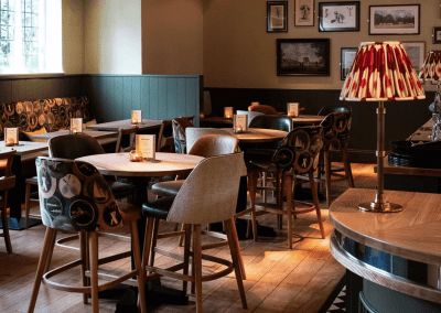 Bespoke pub furniture and soft furnishings at The Long Hop Pub, featuring comfortable seating, dining tables, and curtains designed to complement the venue’s warm, rustic interior.