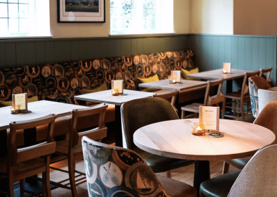 Bespoke pub furniture and soft furnishings at The Long Hop Pub, featuring comfortable seating, dining tables, and curtains designed to complement the venue’s warm, rustic interior.